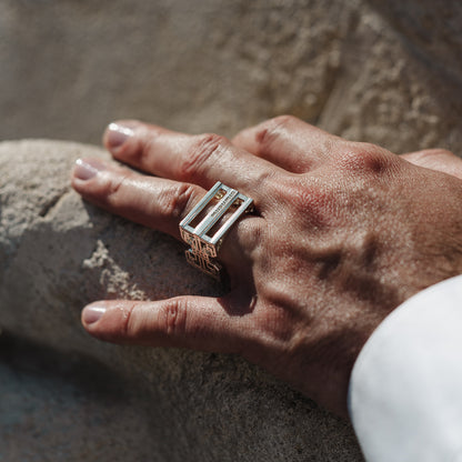 Bague homme en argent 925 hcube2 murumio portée à l'annulaire d'une main posée sur une pierre