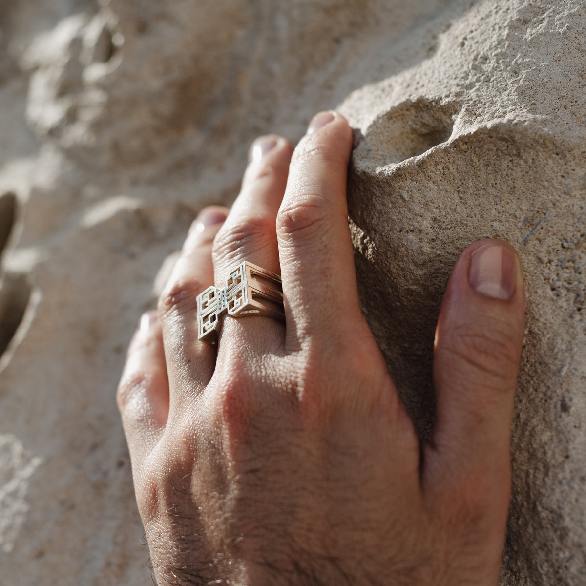 Bague homme en argent 925 hcube2 murumio portée au majeur d'une main posée sur une pierre